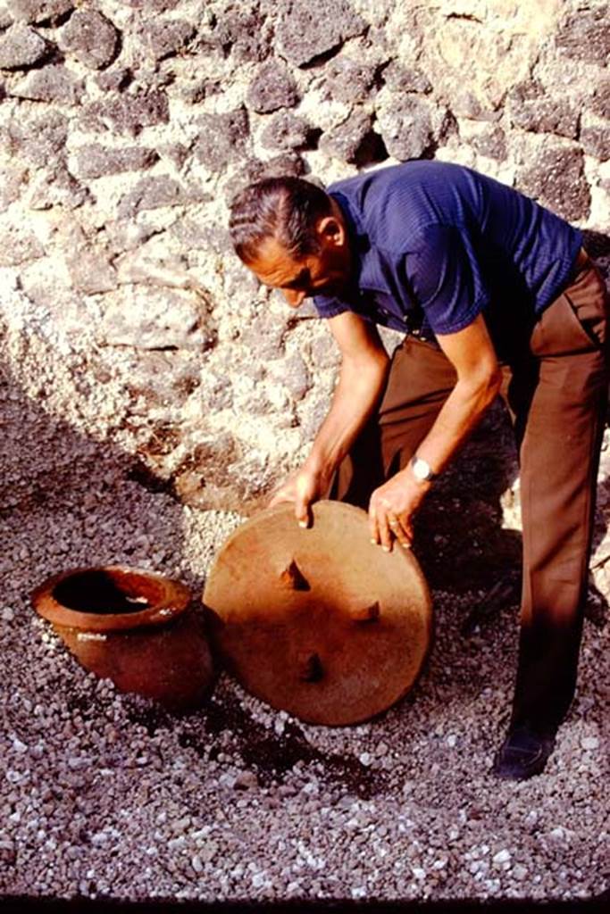 I.21.3 Pompeii. 1974. Removing the lid from the small dolium found buried near east wall. Photo by Stanley A. Jashemski.
Source: The Wilhelmina and Stanley A. Jashemski archive in the University of Maryland Library, Special Collections (See collection page) and made available under the Creative Commons Attribution-Non Commercial License v.4. See Licence and use details. J74f0327