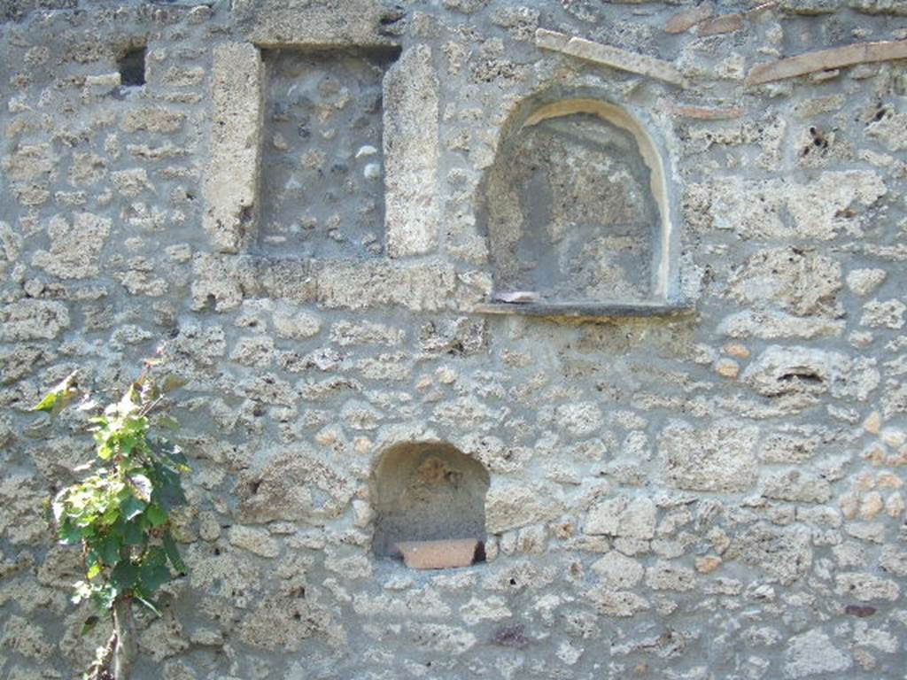 I.21.3 Pompeii. September 2005. In the west wall above the triclinium were three niches. The larger of the two arched niches had a roof tile forming a shelf that reached out into the garden: this niche was undoubtedly a lararium. The smaller and lower of the two arched niches may have held a lamp. The rectangular niche had the appearance of a window that had been only partially walled in. It too may have held a lamp. See Jashemski, W. F., 1993. The Gardens of Pompeii, Volume II: Appendices. New York: Caratzas. (p. 70)