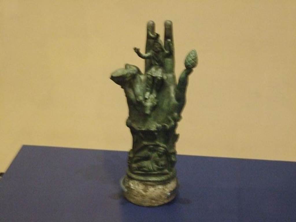 II.1.12 Pompeii. Bronze hand of Sabazius. SAP 10486.
Photographed at “A Day in Pompeii” exhibition at Melbourne Museum. September 2009. According to Berry, SAP 10486 was one of two similar votive hands found in a shrine at the house at II.1.12. Sabazius was sitting in the centre of the palm with his arms raised in benediction. Around the hand are a snake, a caduceus, a knife, a scale and a woman with child.According to Berry, Sabazius was often equated with Zeus or Dionysus. See Berry, J., 2007. The Complete Pompeii. London, Thames & Hudson, (p.200-1). See Conticello, B., Ed, 1990. Rediscovering Pompeii. Rome: L’Erma di Bretschneider. (p.138-139). Both hands, inventory numbers SAP 10485 and 10486 can be seen in Cibi e Sapori a Pompei e Dintorni, (p.37). See Cicirelli, C. (2005): Religio: feste e rituali del culto pubblico e privato, (p.20-38) in the above book.
