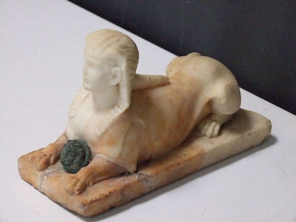 II.2.2 Pompeii. March 2009. Room “i”. White marble statuette of Sphinx, with a face of a bronze gorgon between the front legs. Found on the north side of the upper euripus in the garden in 1920. SAP inventory number 2930.
