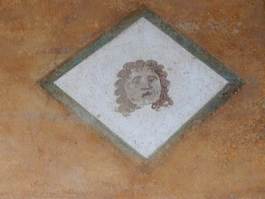II.3.3 Pompeii. May 2016. Room 11, painted face from south end of upper west wall of west portico, above doorway to room 12. Photo courtesy of Buzz Ferebee.