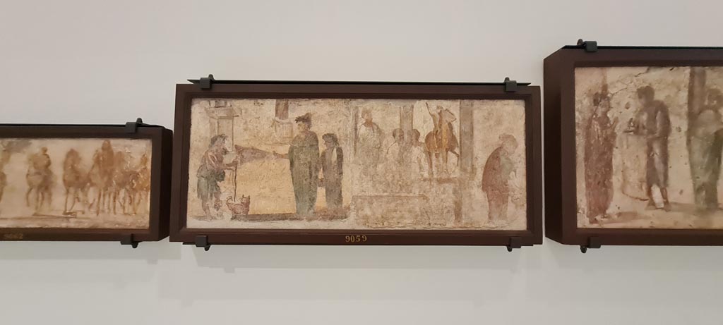 II.4.3 Pompeii. April 2023. Paintings of the Forum frieze, on display in “Campania Romana” gallery in Naples Archaeological Museum.
In centre (inv. 9059) – Mendicante e donne; tre uomini presso statua equestre e donna.
(Beggar and women; three men by an equestrian statue and woman). Photo courtesy of Giuseppe Ciaramella.