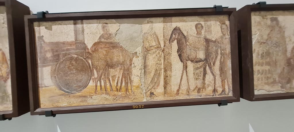 II.4.3 Pompeii. April 2023. Paintings of the Forum frieze, on display in “Campania Romana” gallery in Naples Archaeological Museum.
In centre (inv. 9057) – Carro e uomo; mulo con soma e tre uomini.
(Cart and man; mule with load and three men). Photo courtesy of Giuseppe Ciaramella.