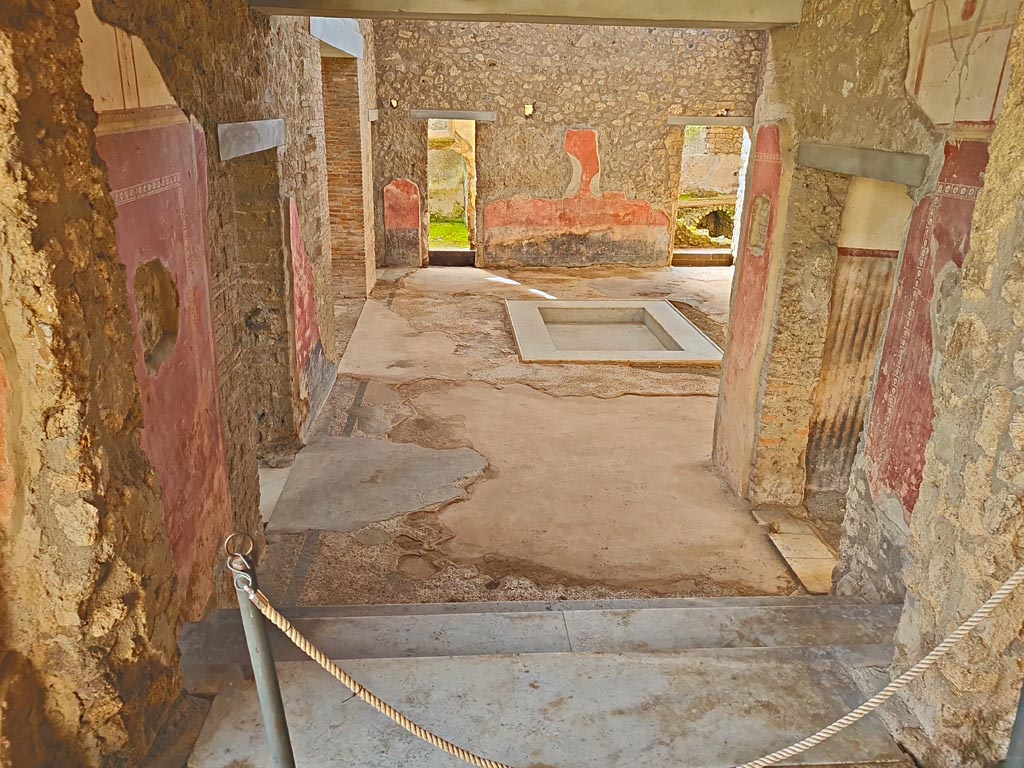 II.4.6/10 Pompeii. March 2024.
Looking south into atrium of II.4.10, from top of steps at south end of portico of II.4.6. Photo courtesy of Giuseppe Ciaramella.
(To view these rooms, see II.4.10.)