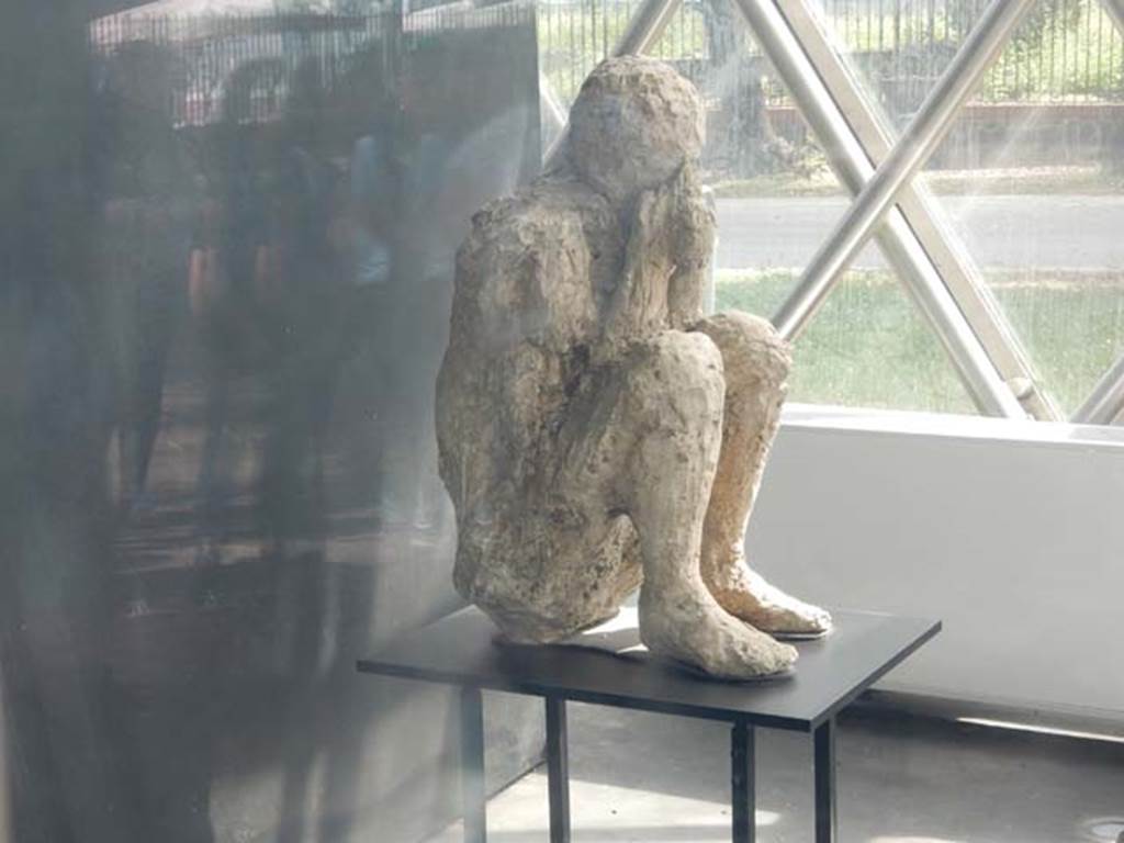 II.7.1 Pompeii. May 2018.
Plaster cast of victim found near the latrine of the Palaestra, perhaps, as portrayed here, found crouching on the ground with his back against the wall of the east portico. Photo courtesy of Buzz Ferebee.
However, when this body was cast, he was found to be tipped forwards, huddled up and bent double on his knees, when restored he was placed in this position.
See Stefani, G. (2010). The Casts, exhibition at Boscoreale Antiquarium, 2010. (p.10).