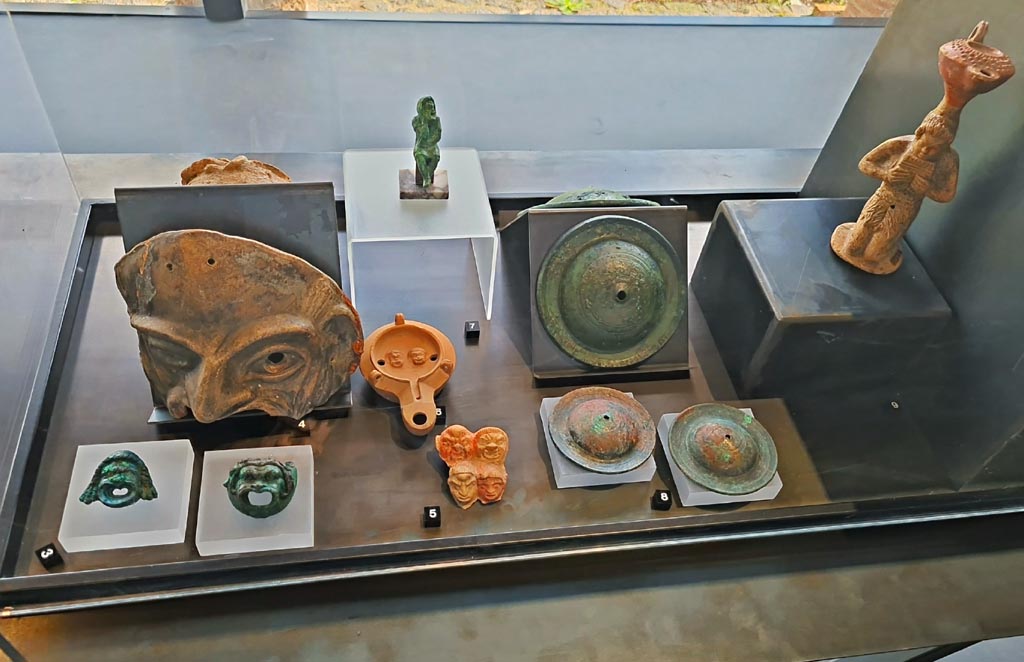 II.7.9 Pompeii. Palaestra. Some items on display in exhibition in Palaestra entitled – “L’altra Pompei, vite comuni all’ombra del Vesuvio”.
March 2024.
No.3 – Bronze wall sconces with theatre masks, from Pompeii.
No.4 – Terracotta theatre masks (2), from Pompeii.
No.5 – Plaque with theatre masks from I.9.13.
No.6 – Oil lamp with theatre masks from I.9.9.
No.7 – Bronze statuette of an actor from I.8.17.
No.8 – Bronze cymbals from Pompeii.
No.9 – Oil lamp with Pan from I.13.2.
Photo courtesy of Giuseppe Ciaramella.