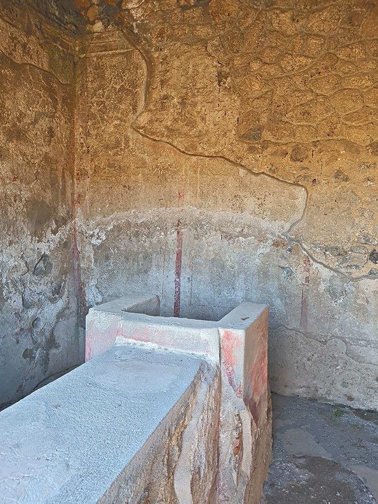 II.8.3 Pompeii. October 2024.
Looking east from entrance doorway towards hearth at end of bar-counter, and decorated east wall.
Photo courtesy of Giuseppe Ciaramella.