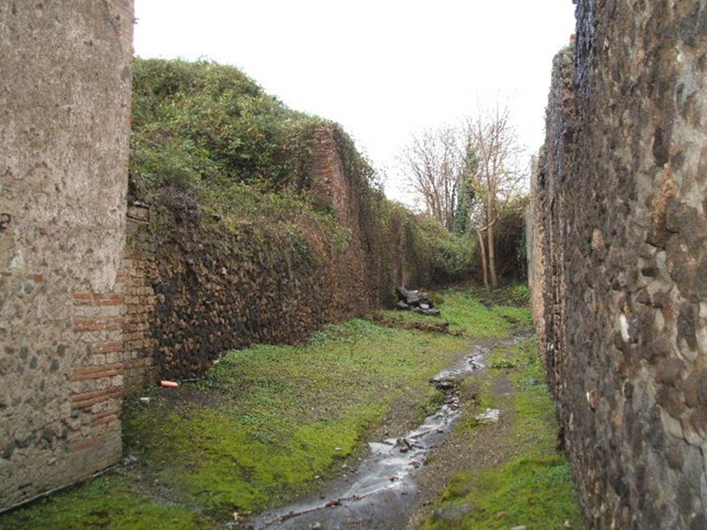 III.3 Pompeii. December 2004. Roadway looking North. Wall of III.4.a