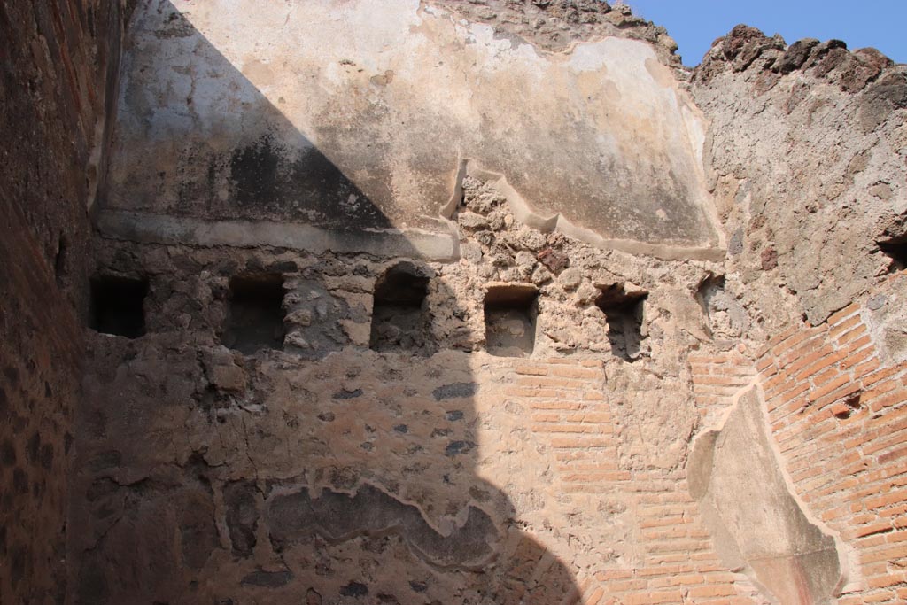 V.1.2 Pompeii. October 2023.
North wall of kitchen/latrine in north-west corner, with holes for support beams for an upper floor.
The upper room has remaining stucco on its north wall. Photo courtesy of Klaus Heese.