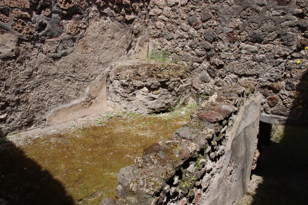 V.1.7 Pompeii. May 2024.
Room “i”, pedestal on east side of storeroom, with ramp to cellars below room “f”, on right. Photo courtesy of Klaus Heese.