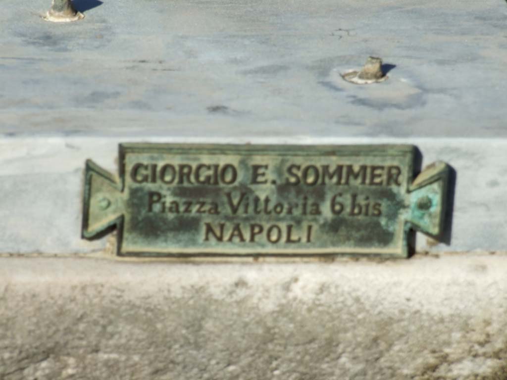 V.1.7 Pompeii. December 2007. Room 1, atrium. Pedestal on impluvium. Plaque with name of Giorgio E. Sommer of Piazza Vittoria 6 bis NAPOLI.
In addition to his photography business, Sommer also had a bronze casting business, making replicas of items in museums and the excavations.