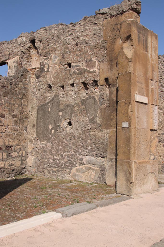 V.1.8 Pompeii. October 2023.
East side of entrance doorway and east wall of shop-room. Photo courtesy of Klaus Heese.
An upper storey latrine can be seen in the upper north-east corner of the shop-room.