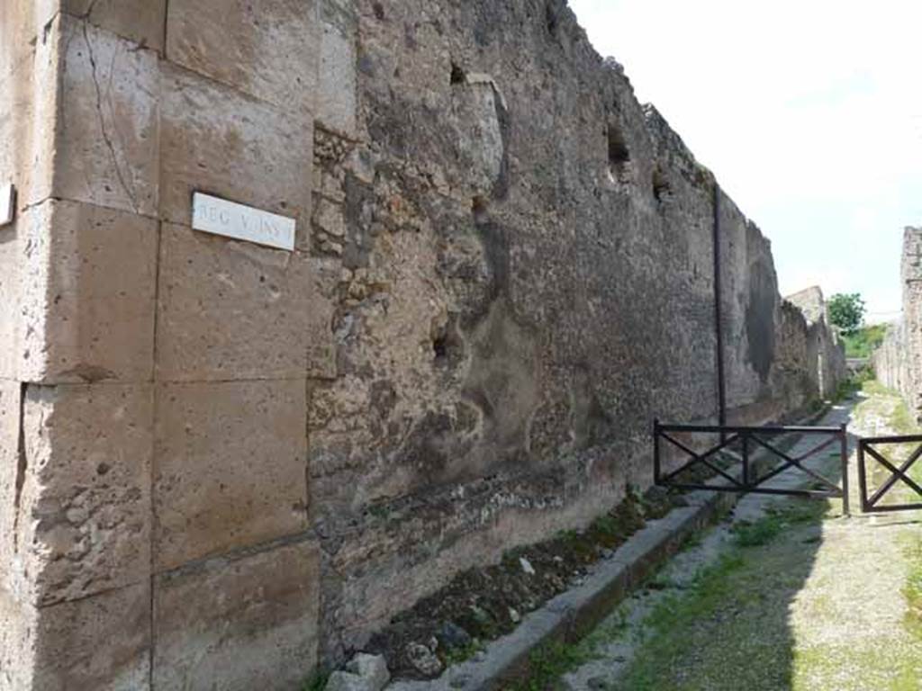V.1.8 Pompeii. May 2010.
Exterior of east wall of shop on west side of Vicolo di Cecilio Giocondo, looking north from junction with Via di Nola.