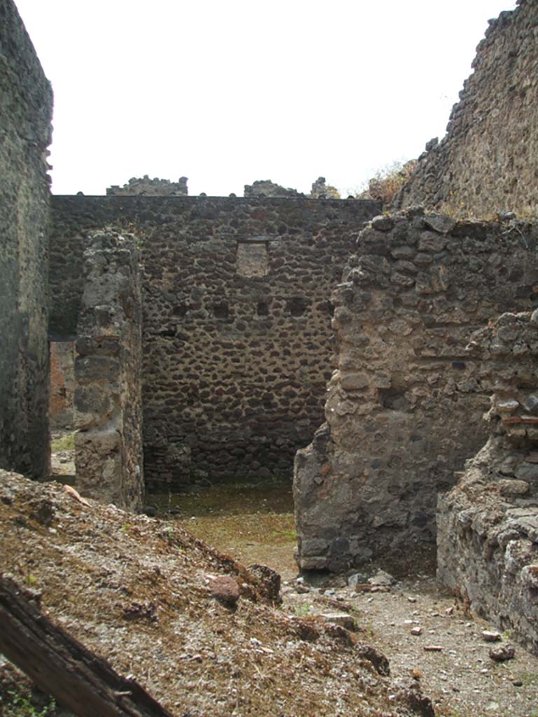V.1.10 Pompeii. May 2005. Looking west from doorway into kitchen and workshop/stable area.
According to Boyce, in the kitchen on the wall beside the hearth was a lararium painting (on the right of this photo).
No longer visible.
See Boyce G. K., 1937. Corpus of the Lararia of Pompeii. Rome: MAAR 14. (p.32)