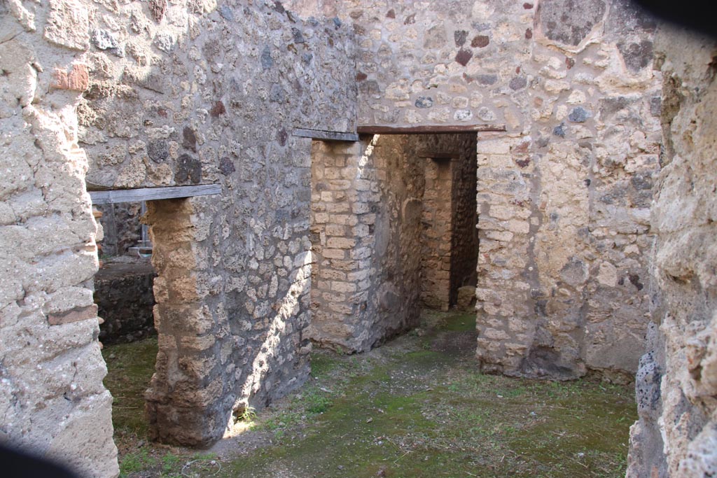 V.1.11 Pompeii. October 2023.
Looking south-east from entrance doorway towards latrine with low doorway, then kitchen doorway, followed by corridor leading into V.1.18.
Photo courtesy of Klaus Heese.