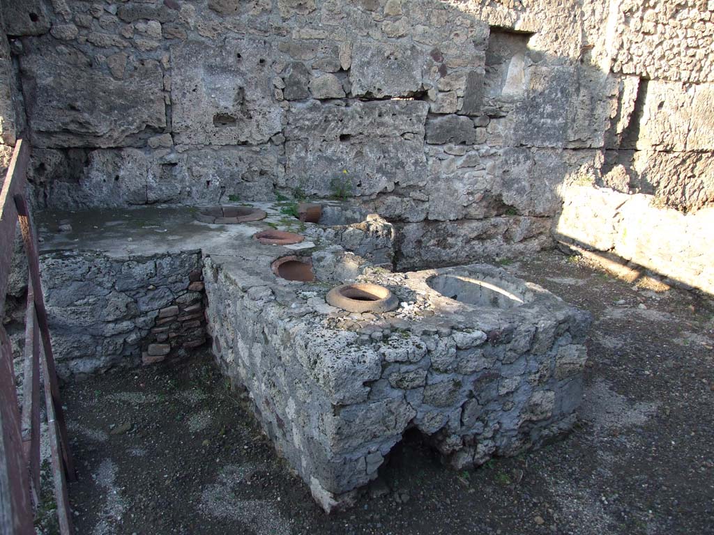 V.I.13 Pompeii. December 2006. Counter, looking north. According to Packer – 
“The U-shaped counter included 6 sunken dolia, it originally had a marble veneer, and a marble herm (a bearded Bacchus) was built into the south side.”
See - Packer, Jim: Inns at Pompeii: a short survey. In Cronache Pompeiane, IV, 1978, (p.40, and note 79).
Note 79: Owing to the partial destruction of the counter and its subsequent repair, its present appearance is entirely different.
A photograph of the counter’s appearance before it was incorrectly restored can be seen in the unpublished M.A. dissertation of S.M. Ruddell.
See Ruddell, S.M. The Inn, Restaurant and Tavern Business in Ancient Pompeii. Department of History, University of Maryland, 1964.
According to Mau, the small marble herm (0.52 high) of bearded Bacchus had traces of reddish colour in his hair.
See Mau, Bullettino dell’Instituto di Corrispondenza Archeologica (DAIR), 1877, p.135.
