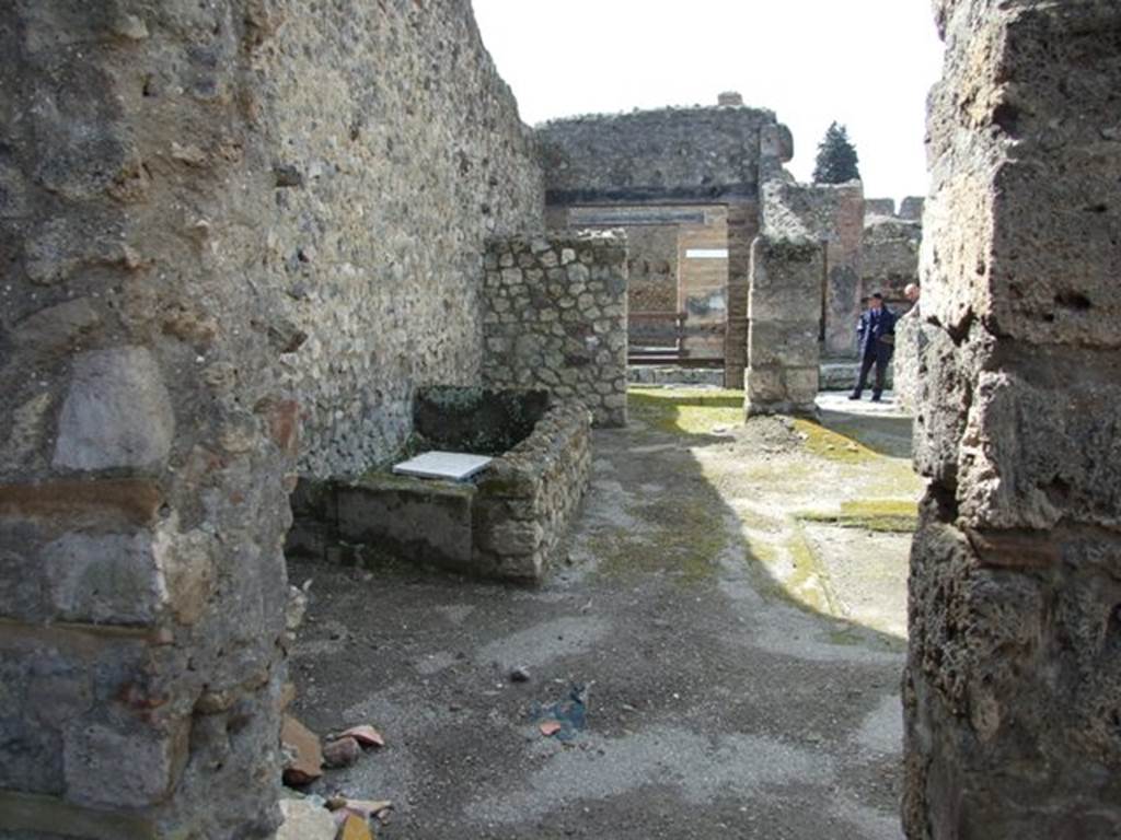 V.1.15 Pompeii. April 2009. Doorway in west wall from Room on south side of Bakery. Looking west into atrium with water basin against south wall.