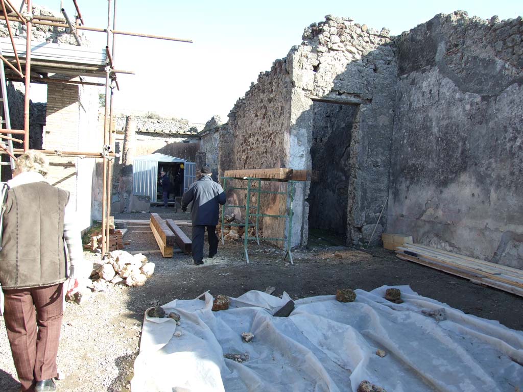 V.1.18 Pompeii. December 2007. Looking east across atrium to tablinum “g” and room “f”.
According to Mau, there were large red panels, divided by narrow black strips each containing a yellow candelabra.
In the centre each red panel was a medallion with the bust of a divinity.
There were originally seven medallions with busts of gods and goddesses, but one had vanished.
The execution was not diligent, but with enough skill to look good for those who do not look too closely.
At the top were black outlined rectangles on a white background with second rectangle with red lines inside each.
See Bullettino dell’Instituto di Corrispondenza Archeologica (DAIR), 1877, p. 20.