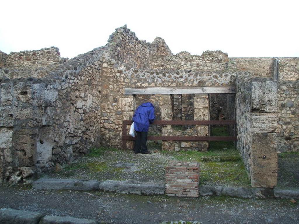 V.1.20 Pompeii. Entrance. December 2004. V.1.20 on left and V.1.21 on right.
According to Mau, V.1.20-21 was a shop or rather workshop, next to the entrance to the steps (21) to the upper rooms, and areas at rear. The steps were not immediately by the door threshold, but were a little way back, so that the steps were also accessible from the workshop. The decorative painting of the workshop, was executed in the last style of Pompeii, and without interest. On the middle compartment of the left wall, we see represented a standing Bacchus crowned with vine, naked except for a blue garment on his left shoulder and right arm, and, as it seems, boots. The right arm raised with thyrsus, while the left hand poured the wine into the mouth of the lying down panther from a jug. The figure was 0.55 high. Hardly recognisable were the paintings from the side panels of the same wall: to the right there were some beasts, perhaps goats. At the rear on the left, was a room used probably by the customers of the workshop; it received light from the workshop itself by means of a window to the right of the entrance doorway. Another door at the rear of the room, whose walls were covered with red coloured plaster, and a corridor that bordered it on the right, both lead to the kitchen. The kitchen had the lararium painting on the left wall, above both the hearth and the well that was to the right, of which not much remained other than a part of the serpent that was shown going towards the doorway of the small room mentioned, away from the hearth. To the right of the entrance to the kitchen there was a low raised quadrangle of material, of uncertain use. At the rear of the kitchen on the left, near to the well and the hearth, a rather high doorway gave access to a small room, 1.13 wide, 1.86 deep of the usual form, but of which I couldn't guess the use. The floor was of opus Signinum; all around ran a gutter, separated from the space it was surrounded by a small wall 0.24 high, also covered by opus Signinum, the gutter at the front corner to the right, crossing the wall, led to the middle part of the room, which towards this point was lower and here had a drain into the well. A vaulted window, in the right wall, gave into a rough room of equal depth, accessible from the kitchen by a low door; the window was made in a manner that its floor lowered towards this last room. See Mau, Bdl (1877), p.17-18