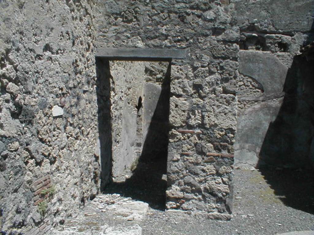 V.1.31 Pompeii. May 2005. North side of shop, passage with vaulted latrine at rear left, and remains of base of stairs, in foreground.