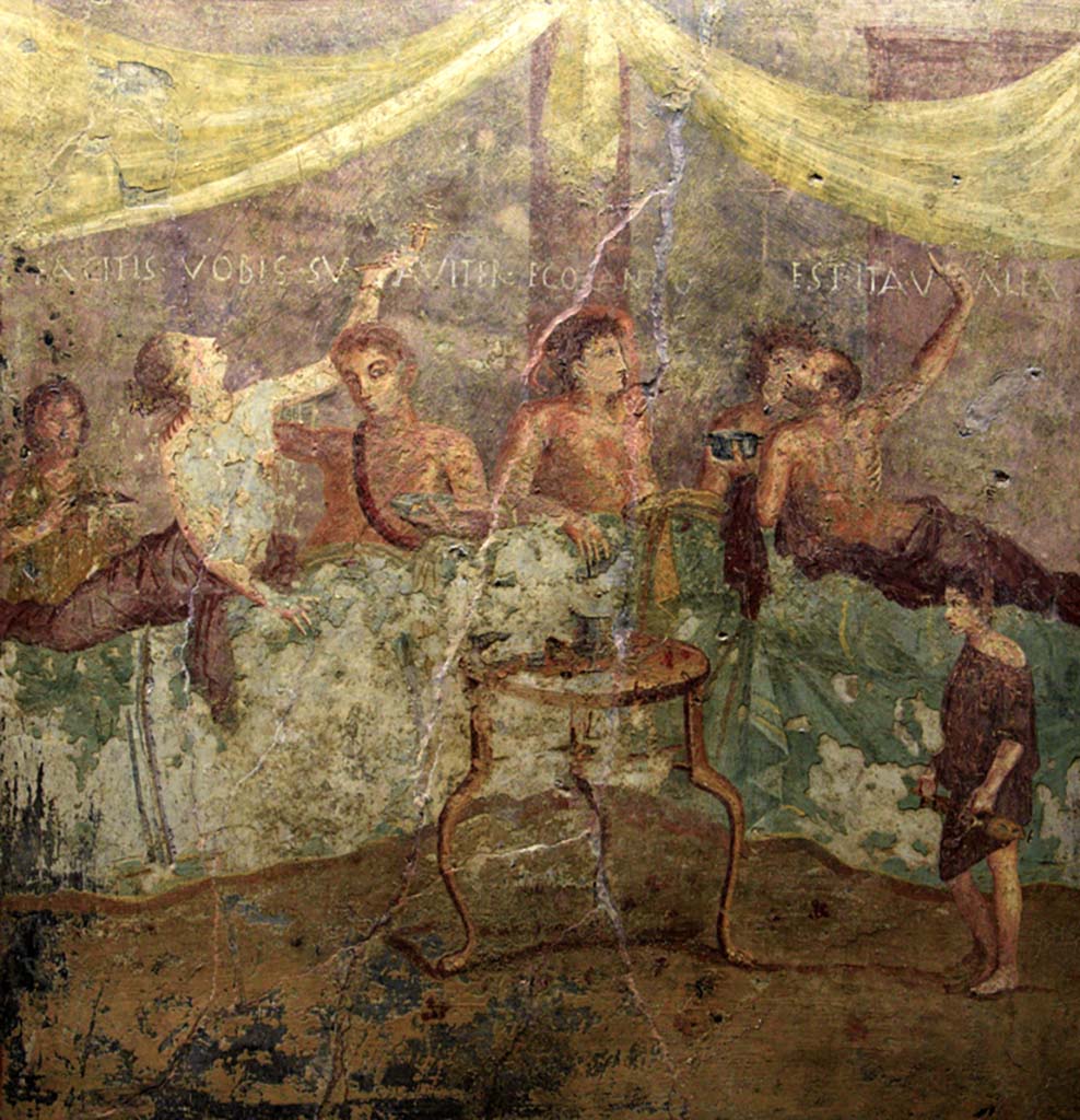 V.2.4 Pompeii. June 2017. Room 15, painting of banqueting scene from north wall of triclinium showing the Commencement.
The guests are reclining at table and a boy brings in dishes. Photo courtesy of Johannes Eber.