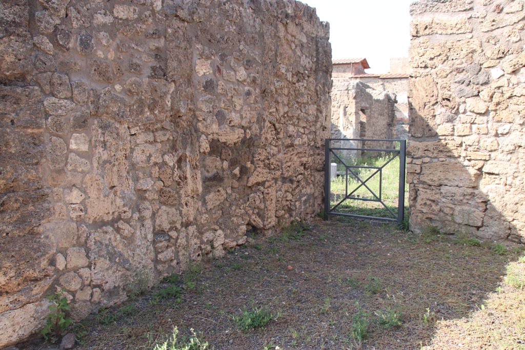 V.2.11 Pompeii. October 2023.
Looking north along west wall of shop-room, towards doorway into V.2.10 in north-west corner. Photo courtesy of Klaus Heese.