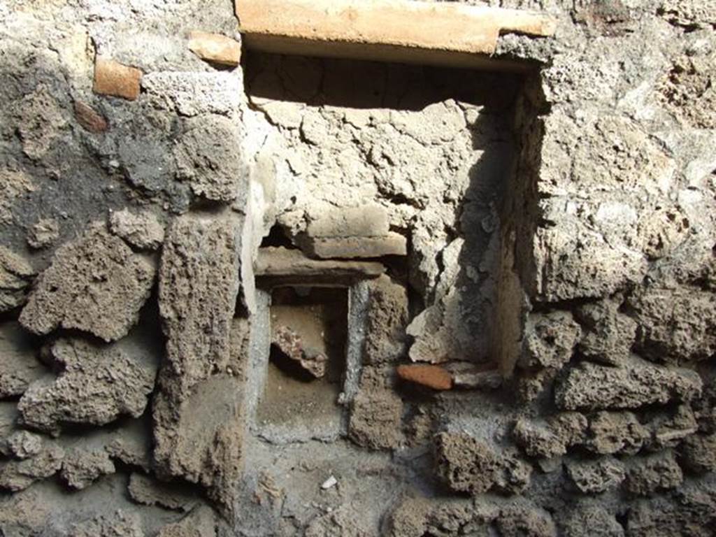 V.2.15 Pompeii. December 2007. Room 11d, rectangular niche. According to Boyce, Mau described this as a lararium. The walls were coated with white stucco, and in the floor were three holes for the bases of statuettes. The walls around the niche were covered with the same white stucco. In the wall below, a semicircular receptacle of terracotta was embedded in the floor of an arched niche. In the bottom of the terracotta was a round hole, as if for drainage, which suggested a connection with the water supply. Today, there is not much remaining.
See Boyce G. K., 1937. Corpus of the Lararia of Pompeii. Rome: MAAR 14. (no.97 on p. 35)