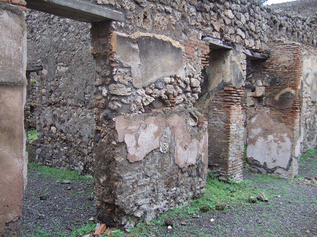 V.2.e Pompeii. December 2005. Three doorways on the north side of the atrium.
The left doorway leading to a room with a window in the east wall overlooking the garden.
The middle doorway leading to steps to upper floor with recess beneath.
The last doorway, on the right, leading to the garden area, the kitchen and a cubiculum.
See Eschebach, L., 1993. Gebäudeverzeichnis und Stadtplan der antiken Stadt Pompeji. Köln: Böhlau. (p.136)