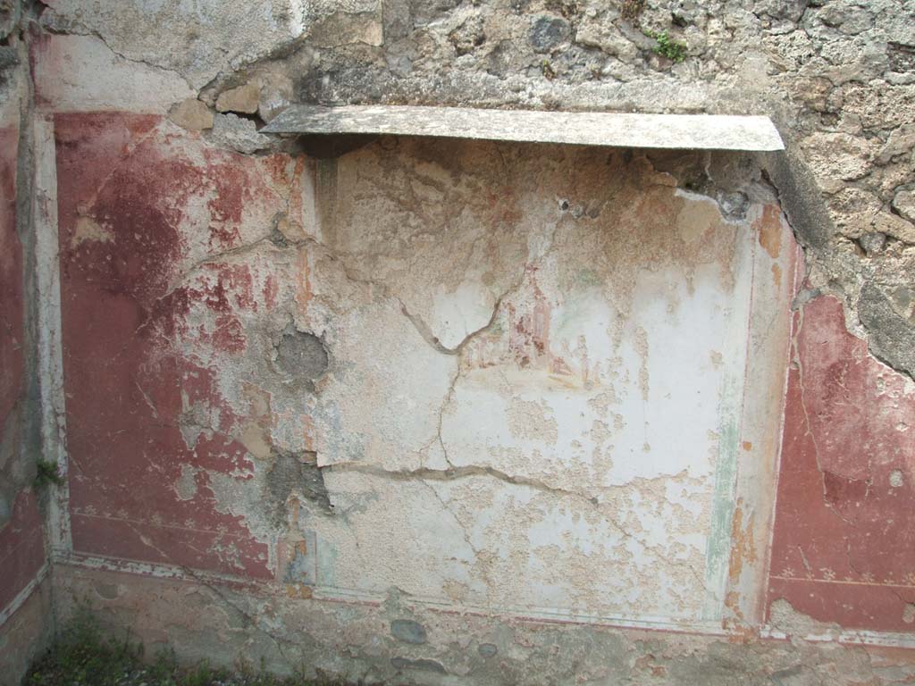 V.2.g Pompeii. May 2005. North wall of room ‘e’, the cubiculum on west side of entrance doorway.
The walls of the cubiculum were decorated with panels of violet.
In the middle of each wall they changed to a white panel, containing the usual rural shrine, here quite crudely painted. 
In the middle of the violet panels, flying animals could be seen, such as swans, sphinxes, griffins and tigers.
The frieze was on a white background, divided into panels by stripes of many colours.
In the two lunettes of the vault, fruits and pecking birds were painted.
In the middle of the north lunette was a window overlooking the vicolo.
The yellow dado would have imitated coloured marble.
In general, the decoration was very mediocre.
See Notizie degli Scavi di Antichità, 1896, (p.419)
