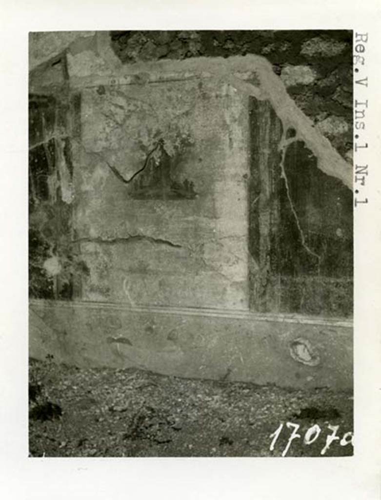 V.2.g Pompeii. 1937-39. North wall of room ‘e’, the cubiculum on west side of entrance doorway. Photo courtesy of American Academy in Rome, Photographic Archive.  Warsher collection no. 1707a
According to PPM, when discovered this north wall had a pink zoccolo sprinkled with red and white. The middle zone of the wall had three panels, the middle one being white with the painted sacred landscape, shown above. The side panels were red with borders edged in “carpet” style and a line, containing a small painting in the centre (griffins, etc). These panels were separated by a narrow black compartment.
The upper zone of the wall was white and showed traces of a green painted garland.
