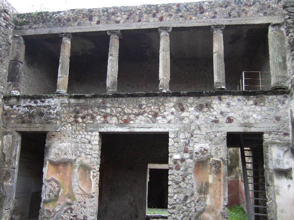 V.2.h Pompeii. December 2005. South side of atrium. Doorways to cubiculum ‘g’, tablinum ‘f’ (in centre), and room ‘e’ with stairs. According to NdS, the floor of the atrium was Opus signinum, and the walls were covered with a rustic white plaster, except the two walls flanking the doorway to the tablinum, which were decorated with a yellow background and a black dado. On the yellow part was a painted peacock of more or less its natural size, before which, on the wall to the right, was a basket full of grapes, and on that to the left were fruits (pomegranates?) placed on the ground. In both of the walls to the sides of the tablinum, traces of fire could be seen.