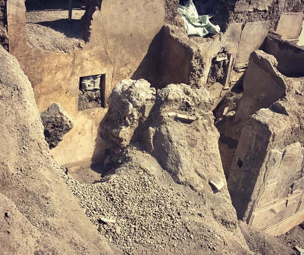 V.2.Pompeii. Casa di Orione. May 2018. Room A17 on the south side during excavation.
Photograph © Parco Archeologico di Pompei.
This room was the kitchen, a “service room” recognised by its simple decoration and the presence on the floor 
of various artefacts from table and pantry (cooking pots and tablewares) and amphorae, as well as from the finding near to the east wall of a square structure that defined a masonry hearth.  There at the time of excavation, the ash of the last baking/cooking was still preserved, covered by the upper portion of an amphora which was to serve as a lid. Presumably, the last cooked meal, and perhaps never eaten, by the owner of the house.
See Osanna M, 2019. Pompei. Il tempo ritrovato. Le Nuove Scoperte. Milano: Rizzoli, (p.99).


