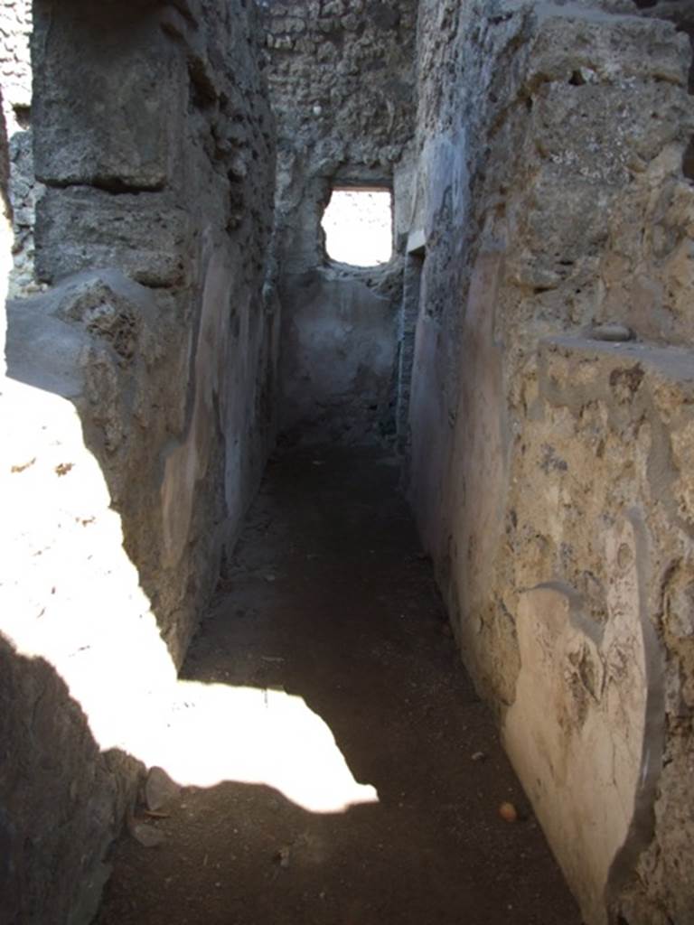 V.3.4 Pompeii. March 2009. Corridor leading east, to small room on the south side.
According to Sogliano, this corridor on the north side of the front room had wooden door-jambs at the entrance. The walls were lined with rough plaster with a high brick plinth.
On the right, immediately upon entering the corridor, he saw a small niche which had side walls clad in wood. Facing it in the left wall was a rectangular window, fitted with the equal of a sill and jambs made of wood. A second window was at the end of the corridor.
A doorway at the end led into a small room or cupboard. See Notizie degli Scavi di Antichità, 1905, (p. 209)