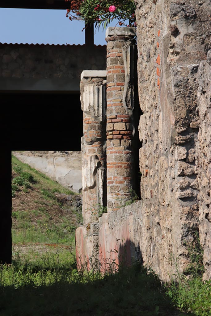 V.3.4 Pompeii. October 2023.
Looking north from entrance doorway towards two white stuccoed columns on west side of garden, which supported the west and partial north portico.
Photo courtesy of Klaus Heese.