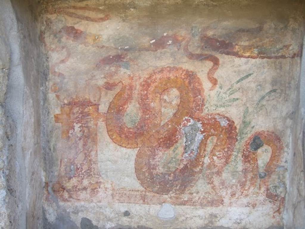 V.3.7 Pompeii. March 2009. West wall of garden area. Lararium upper zone. This has a painting of a serpent advancing left to a round altar which is painted in a variegated marble style. In the background are plants and a double garland is across the top. See Boyce G. K., 1937. Corpus of the Lararia of Pompeii. Rome: MAAR 14. (112, p. 38, Pl 36, 2).