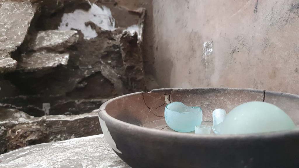 V.3.13 Pompeii. 2022. Room 3b, bedroom.
Ceramic cup containing two glass ampoules.
Una coppa in ceramica contenente due ampolline in vetro.
Photograph © Parco Archeologico di Pompei.