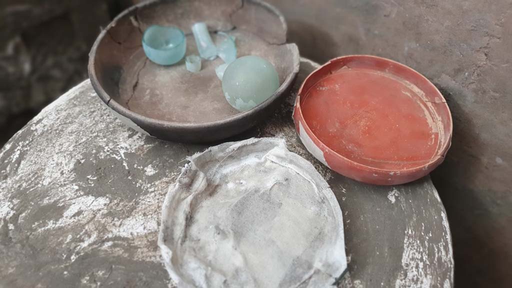 V.3.13 Pompeii. 2022. Room 3b, bedroom.
On the table was a ceramic cup containing two glass ampoules, a small sigillata plate and another small glass plate.
Sul tavolino circolare a tre piedi c’era una coppa in ceramica contenente due ampolline in vetro, un piattino in sigillata ed un altro piattino in vetro.
Photograph © Parco Archeologico di Pompei.