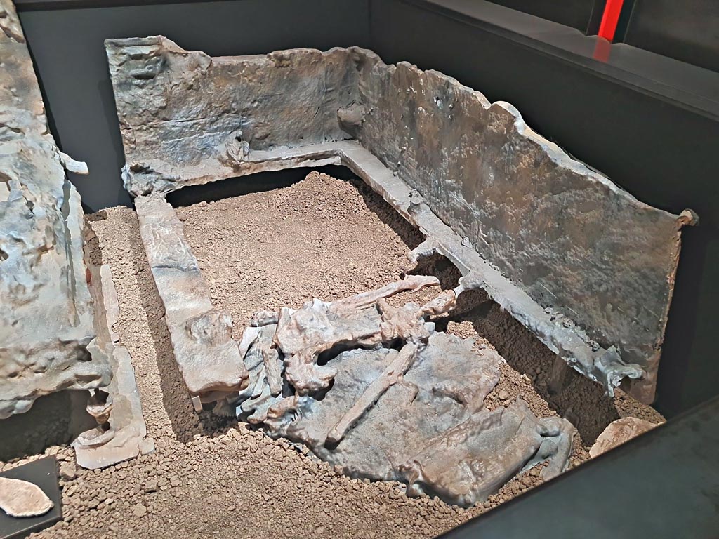 V.3.14 Pompeii. March 2024.
Room 16, casts of bed 2, letto 2 on the plan, and the furnishings (the bed is a copy, while the sole of the shoe, lower left, is original.)
On display in exhibition in Palaestra entitled “L’altra Pompei, vite comuni all’ombra del Vesuvio”. Photo courtesy of Giuseppe Ciaramella.