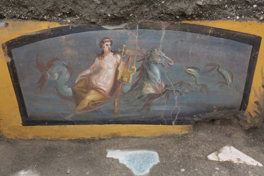 V.3 Pompeii. March 2019. The richly decorated Thermopolium in the open space which acts as a crossroads between Vicolo delle Nozze d’Argento and Vicolo dei Balconi. 
Painting of the beautiful figure of a Nereid holding a lyre, sitting on a marine horse with two dolphins swimming at the side.

V.3 Pompei. Marzo 2019. Termopolio all'incrocio tra il Vicolo delle Nozze d'Argento e il Vicolo dei Balconi.
Dipinto della bella figura di una Nereide che regge una lira, seduta su un cavallo marino con due delfini che nuotano ai lati.

Photograph © of Parco Archeologico di Pompei.
