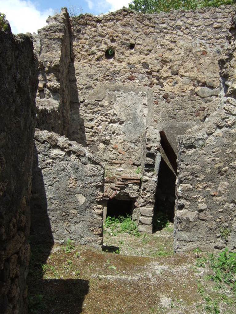 V.4.a Pompeii. May 2006. Kitchen area, looking north. According to Boyce, on the west wall of the kitchen entered from the north-west corner of the peristyle, was a fragmentary Lararium painting. One figure of a Lar was preserved, as well as the Genius pouring a libation, a Camillus, and below one red and yellow serpent advancing to the right.
A second and smaller picture had been subsequently painted over the top of that one, but only one Lar remained of that one too. On the south wall, to the left of the entrance, was painted a ham.
See Boyce G. K., 1937. Corpus of the Lararia of Pompeii. Rome: MAAR 14. (p.42, no.128)