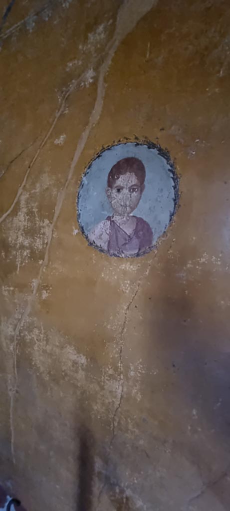 V.4.a Pompeii. January 2023.
Room ‘i’, medallion with painting of girl on west wall of cubiculum on south side of doorway to atrium.
Photo courtesy of Miriam Colomer.