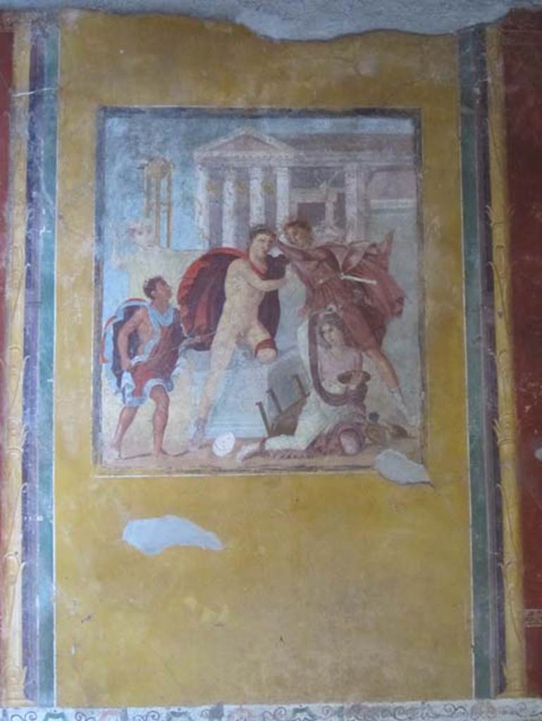 V.4.a Pompeii. March 2012. Central panel on east wall with wall painting of Orestes killing Neoptolemus at the altar before the Temple of Apollo at Delphi. Photo courtesy of Marina Fuxa.