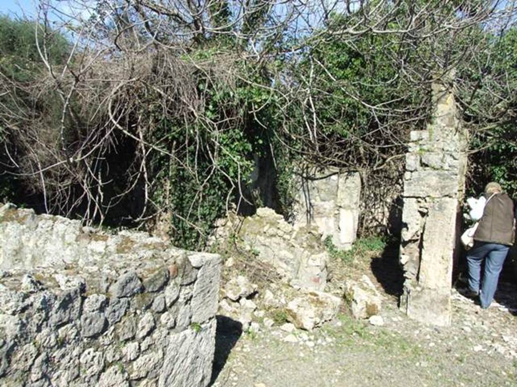 V.4.c Pompeii. March 2009. Ruined doorway of room F, cubiculum or rustic room in the north-east corner of atrium B. Looking east from restored wall of triclinium D, across room E, ala, towards to room F. In the east wall of the ala, the doorway to rustic room F was found. It would have had a wooden threshold, a mortar floor, and white stucco on the walls. In the south wall, at a height of 0.95m from the ground, a small area was found with traces of shelving. See Notizie degli Scavi, 1905, (p.133).
