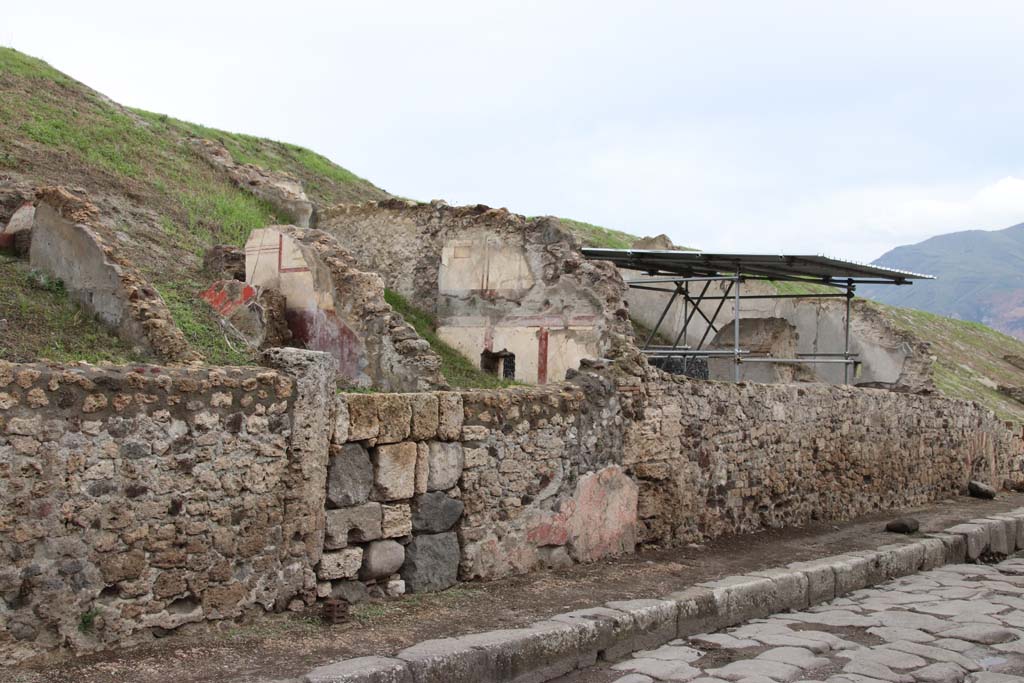 V.6.7 or 8 Pompeii, Pompeii. October 2020. Looking south along east side of Via del Vesuvio. Photo courtesy of Klaus Heese.
(Note: the roofed area where the lararium is seen above the wall, originally we had identified as V.6.7.
According to Massimo Osanna's book the lararium area is shown as casa 4 and the three front rooms to the north (left) is casa 3.
There does not seem to be a doorway entering the lararium area from this roadway or casa 3, so perhaps the numbered entrance doorway would be further at the rear, still buried.
Therefore, perhaps the doorway with the large blocks in centre left, is now V.6.7.)
See Osanna M., 2019. Pompei. Il tempo ritrovato. Le nuove scoperte. Milano: Rizzoli, p. 216, fig. 4.