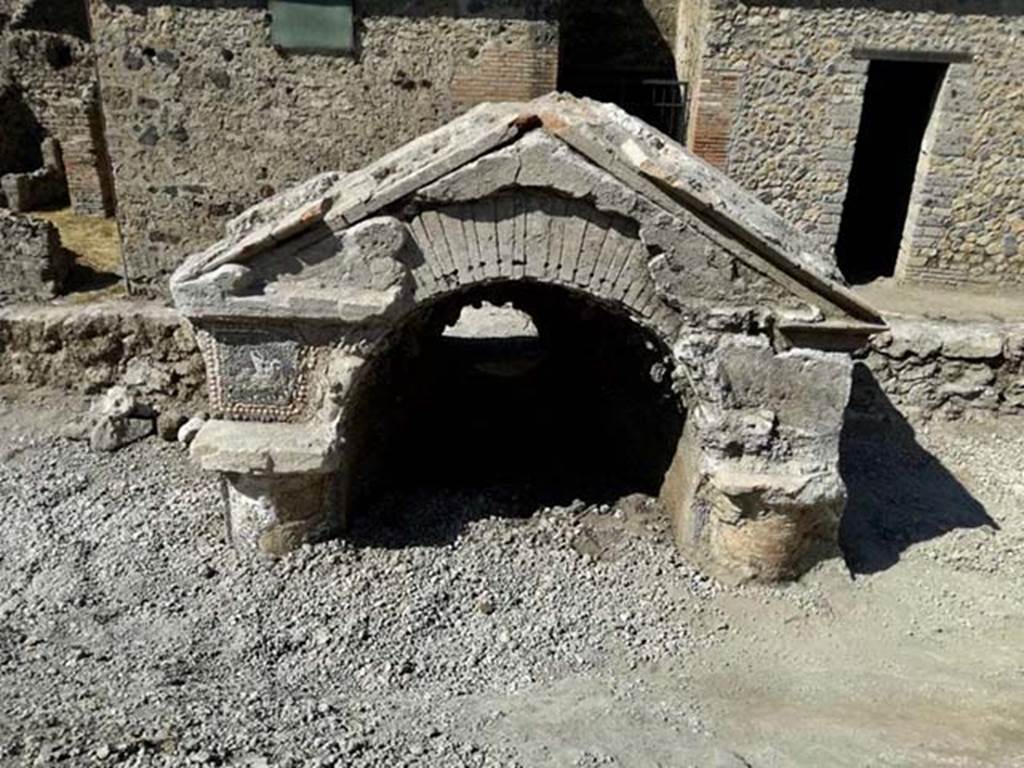 V.6.7 Pompeii. August 2018. Upper part of a fountain / nymphaeum.
The façade is facing the inside of the insula, where a garden probably opened.
The surface so far exposed (upper part of the columns, upper part of the niche and pediment) is covered with vitreous tesserae and shells, which form complex decorative motifs.
A bird is shown above one of the columns. Photograph © Parco Archeologico di Pompei.