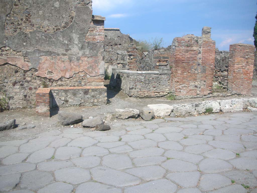 VI.1.3 Pompeii, on right. May 2010.
Looking east across Via Consolare, with entrance at VI.1.2, in centre. Photo courtesy of Ivo van der Graaff.
