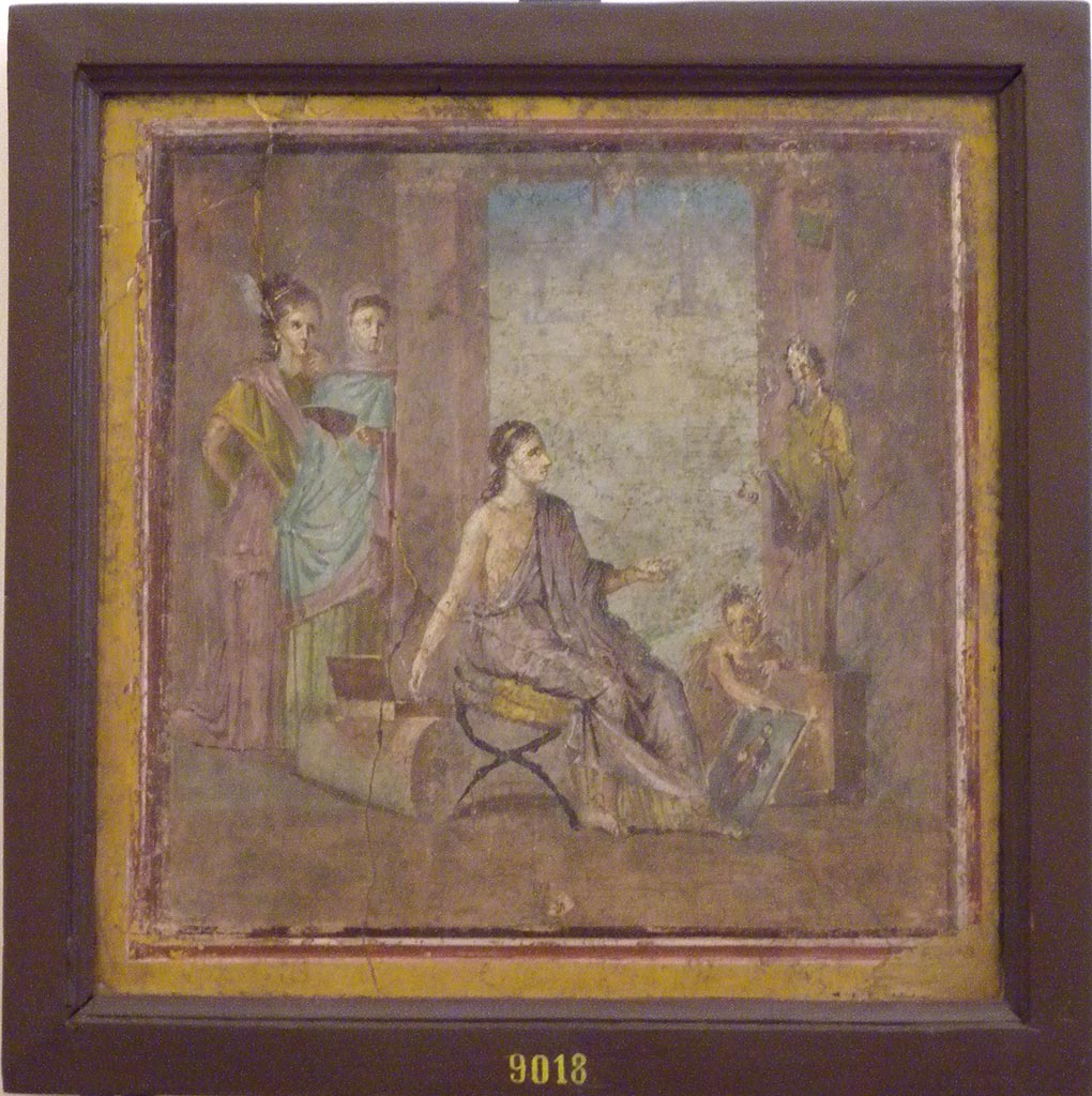 VI.1.10 Pompeii. December 2007. Found 22nd June 1771 on east wall of room 9, room to south of garden.
Wall painting of a young woman painting a herm of Dionysus.
A cupid is holding the unfinished picture while she mixes colours on her palette.
Two other maidens are watching the artist with unfeigned interest.
See Mau, A., 1907, translated by Kelsey F. W. Pompeii: Its Life and Art. New York: Macmillan. (pp. 280-2, T. 133).
Now in Naples Archaeological Museum. Inventory number 9018.