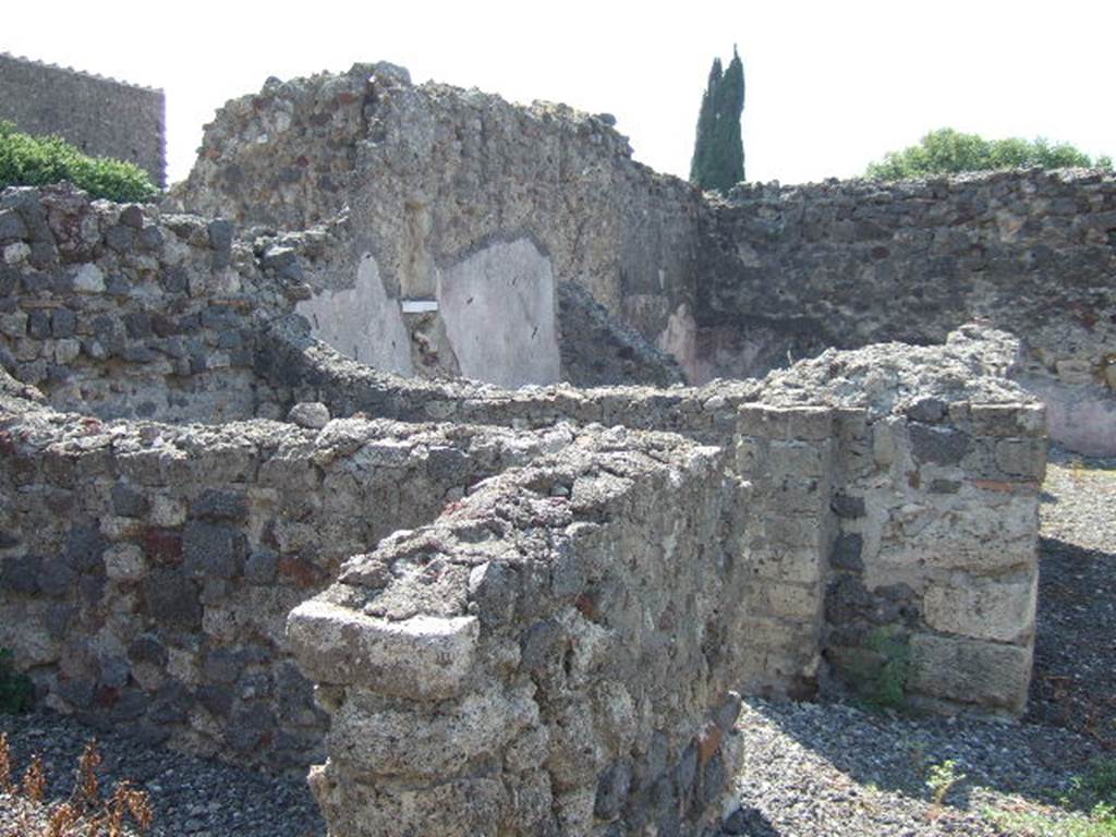 VI.2.28 Pompeii. September 2005. Looking south-west towards rear of house and small garden area. The remains of two cubicula can be seen on the left, and in the upper middle would have been the Oecus.
On the south wall of the oecus, the lararium niche can be made out, above a white shelf. At the rear of the oecus, across the rear of the house, would have been the garden area. According to Giacobello, in the south wall of the Oecus was a square niche with the residue of white plaster and shelf in marble. See Giacobello, F., 2008. Larari Pompeiani: Iconografia e culto dei Lari in ambito domestico. Milano: LED Edizioni. (p.290)
According to Boyce, in the south wall of the oecus which opens off the garden is a rectangular niche. The walls of the niche are coated with stucco and painted green. The floor of the niche is a thick slab of marble; the reports called it la nicchia per I Penati. See Boyce G. K., 1937. Corpus of the Lararia of Pompeii. Rome: MAAR 14. (p.44, no.143)
