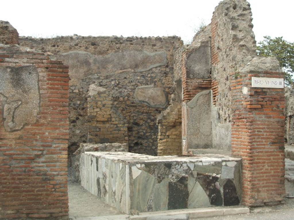 VI.3.20 Pompeii. May 2005. Looking north towards entrance doorway.
There used to be an electoral recommendation, found on the left of the doorway where remains of plaster can still be seen.
According to Della Corte, this is a thermopolium with two rooms annexed for the entertainment of the customers and a rustic room with a staircase leading to the upper floor.
The manageress or owner was a woman, Fortunata, as proved by a painted programma near to one of the doors.
This showed Fortunata recommending the candidate M. Casellio Marcello.
See Della Corte, M., 1965. Case ed Abitanti di Pompei. Napoli: Fausto Fiorentino, p. 42.