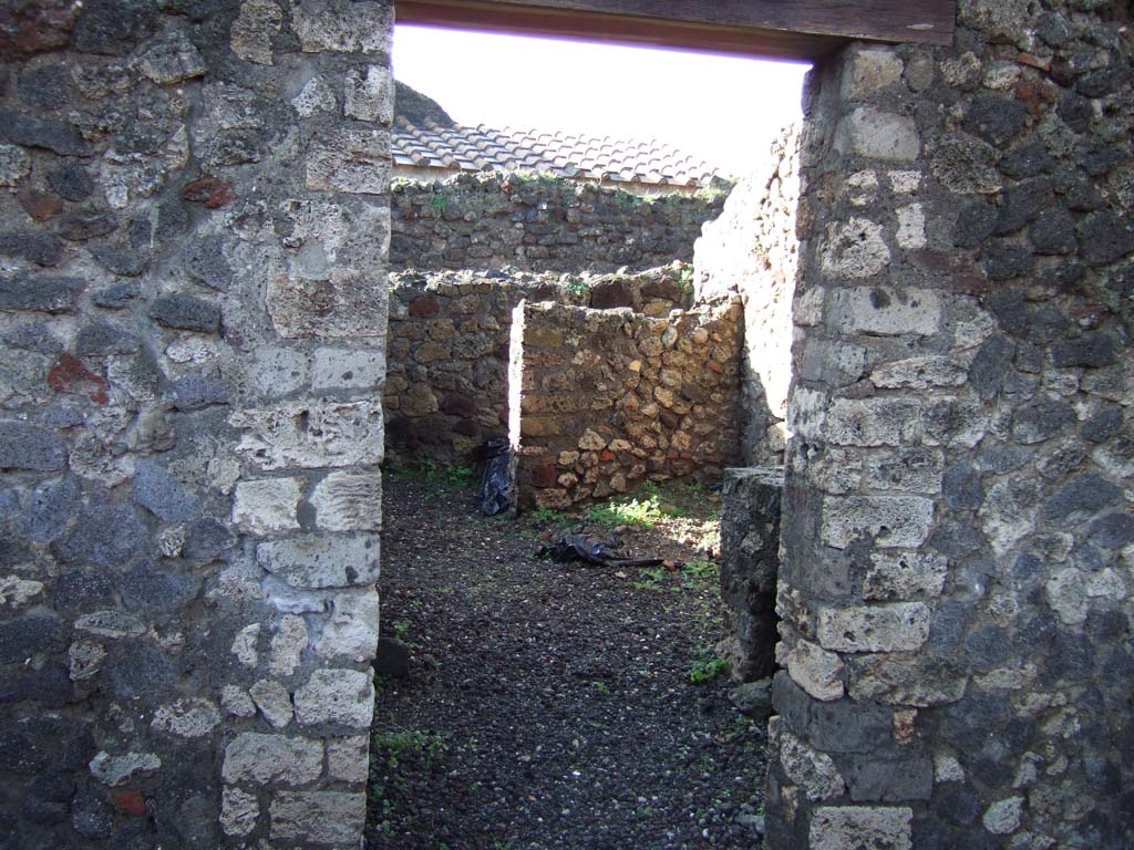 VI.5.14 Pompeii. December 2005. Looking west through doorway into kitchen area
The walls of the latrine can be seen in north-west corner.
The north-west corner of this room, the latrine, shows that today there is no doorway of VI.5.11 here, as shown on Eschebach plan.
VI.5.11, steps to an independent upper floor, is now to the north of this corner, fronting onto Vicolo di Modesto, and is completely separate from here.
According to CTP, the north-west corner of the house at VI.5.14 was excavated in 1817, as well as the pseudoperistyle of VI.5.10 and atrium area of VI.5.9.
The street wall at the north-west corner of the house at VI.5.14 collapsed and was reconstructed, which may provide the reason why Tascone, Mau and Eschebach, all indicated a rear doorway of this house immediately south of the stairway, which, rightfully should be assigned a number.
The doorway is delineated by Russo’s map of 1817, and later by Mazois, Fiorelli – Sorgente, and Zangemeister (1865).
Today the number VI.5.11 is not in situ but it has been assigned by the SANP to the staircase.
See Van der Poel, H. B., 1981. Corpus Topographicum Pompeianum, Part V. Austin: University of Texas. (p.196-7)